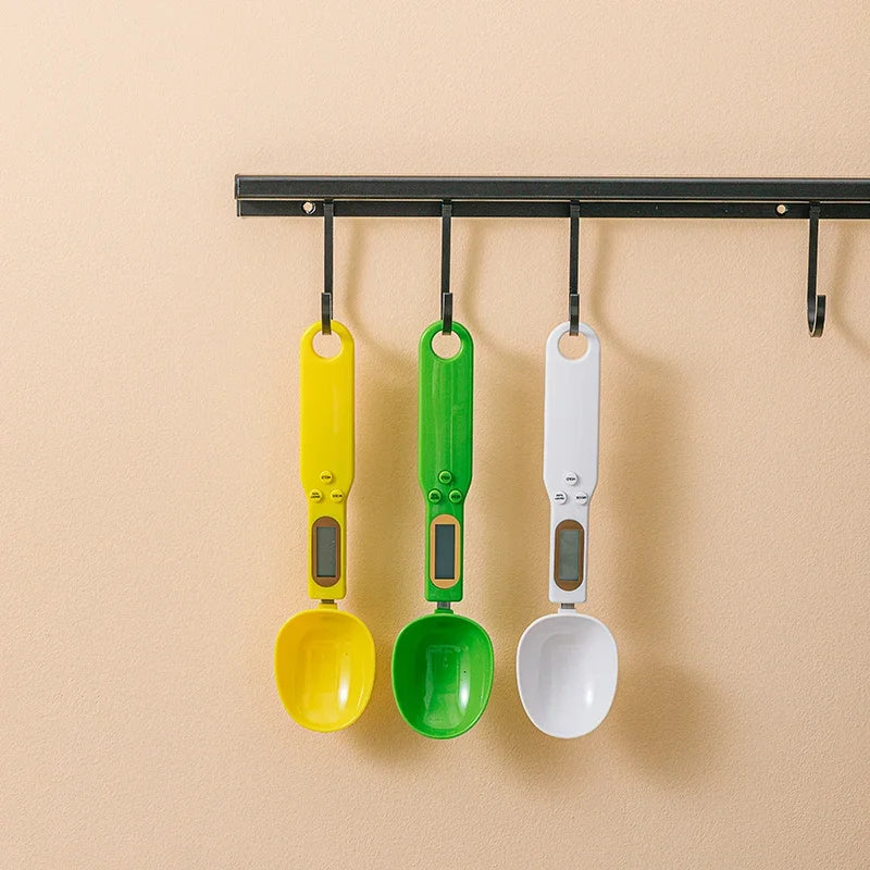Three colorful measuring spoons hanging on a magnetic strip against a beige background