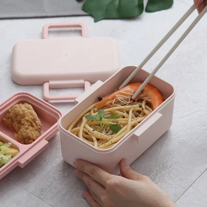 Pink bento box with food compartments on a light surface
