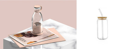 A clear glass bottle with a light wood lid and straw, shown in a styled interior scene on a marble surface next to a magazine, and also as a standalone product shot on a white background.