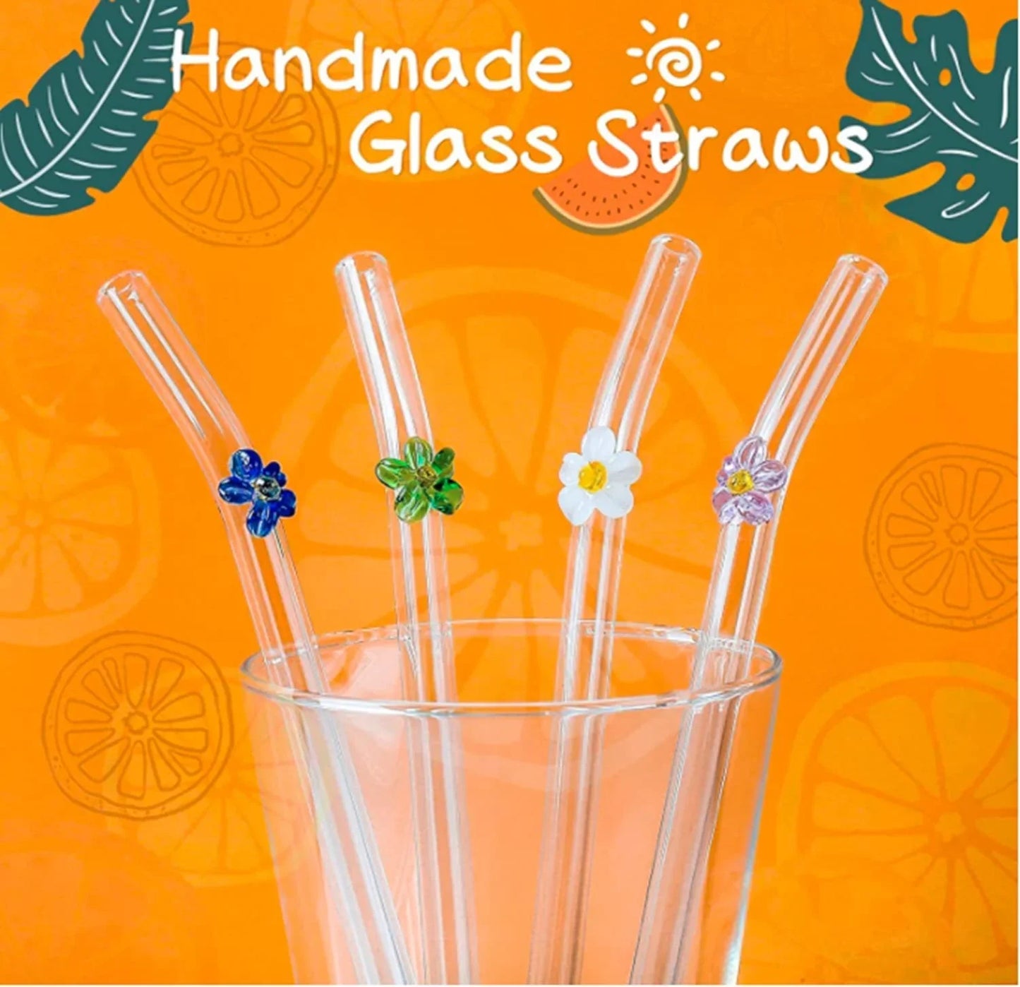 Four clear glass drinking straws with small decorative flower and clover charms in blue, green, white, and purple, arranged in a clear glass on an orange background with the text 'Handmade Glass Straws'.