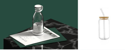 A clear glass bottle with a silver cap and white label sits on an open magazine on a dark marble surface against a dark green background. A second view on the right shows the same bottle with a clear glass straw and light wood lid on a white background.