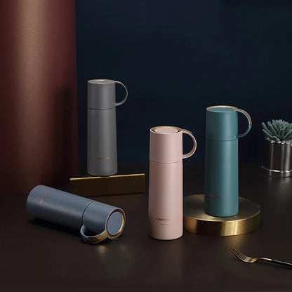 Set of four insulated travel mugs in different colors on a dark surface with a dark background.