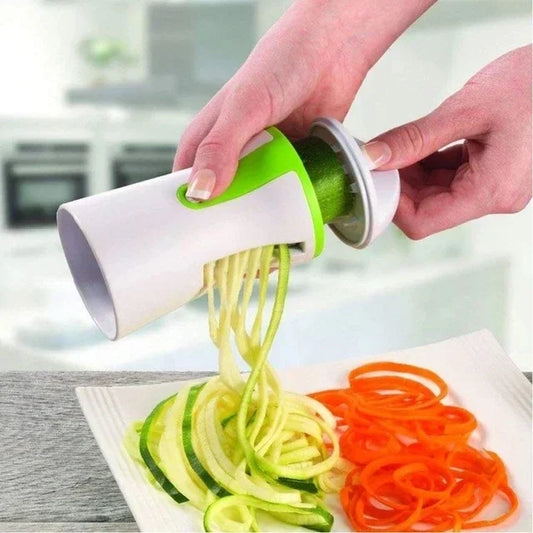 Person using a spiralizer to create zucchini and carrot noodles on a white plate.