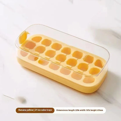 A banana yellow silicone ice cube tray with a clear plastic lid, resting on a light marble surface. Text at the bottom reads 'Banana yellow | 21 ice cube trays Dimensions: length 220x width 167x height 67mm'.