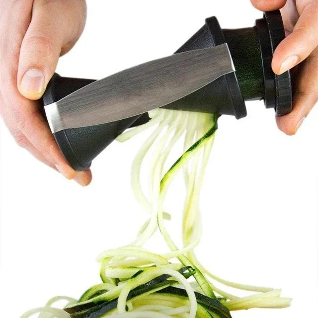 Zucchini being spiralized with a handheld spiralizer on a white background
